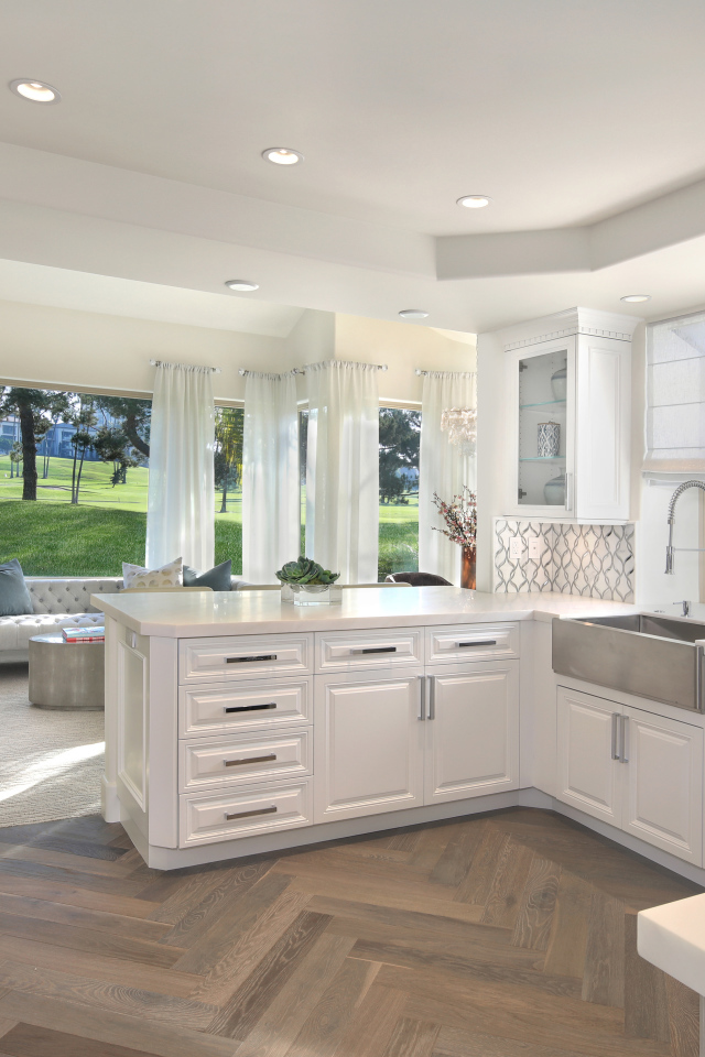 Белый кухонный гарнитур в комнате с большим окном