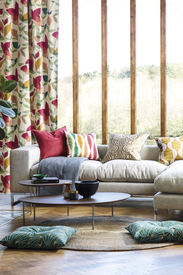 Белый диван с подушками стоит у окна