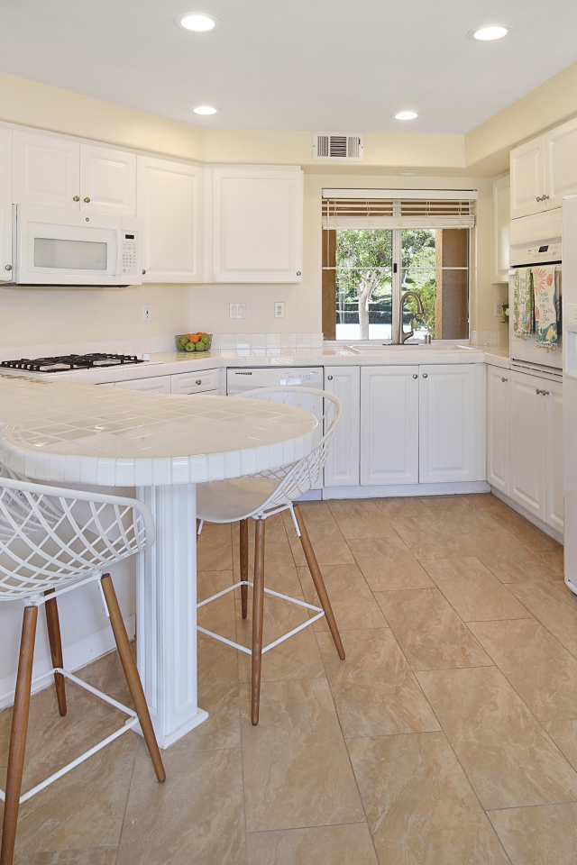 Белая стильная мебель с большим холодильником на кухне