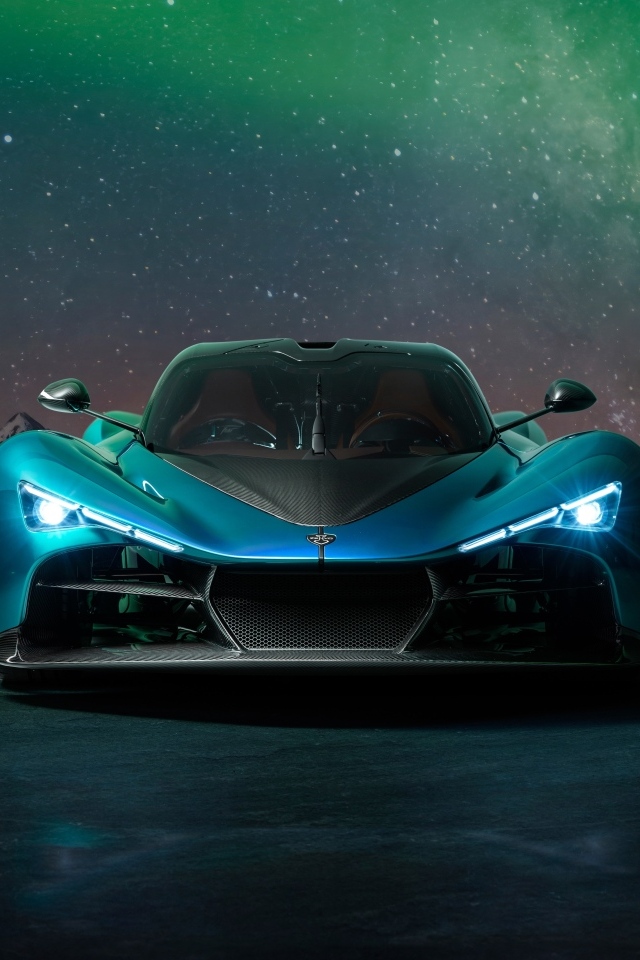Голубой спортивный автомобиль Zenvo Aurora на фоне гор и полярного сияния