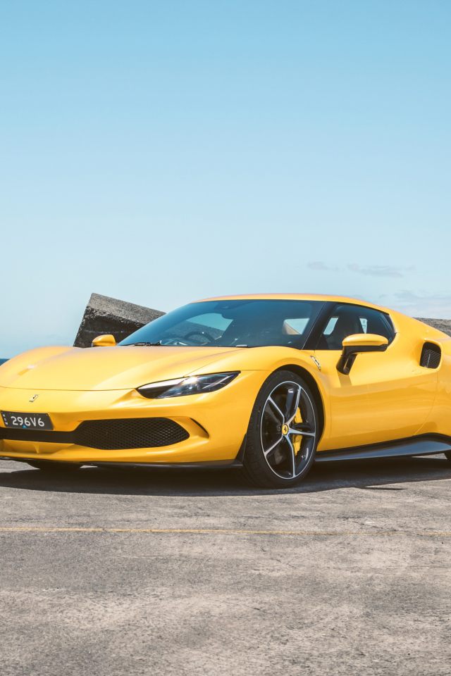 Желтый автомобиль Ferrari 296 GTB у камней