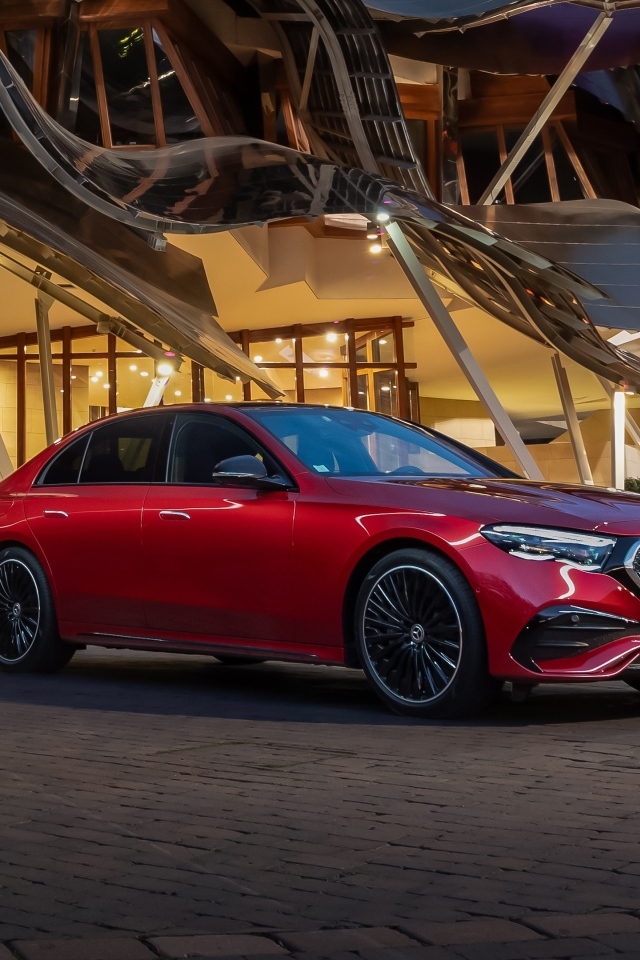 Красный автомобиль Mercedes-Benz E 220 D AMG Line у здания