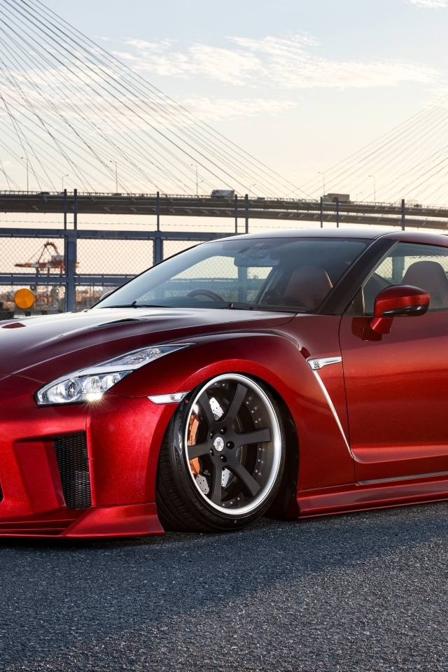 Красный автомобиль Nissan GTR 35R на фоне моста
