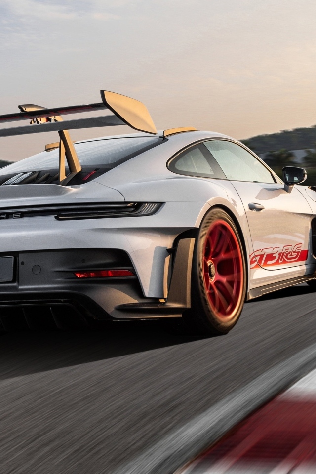 Серебристый спортивный автомобиль Porsche 911 GT3 RS Weissach Package 2023 года на трассе