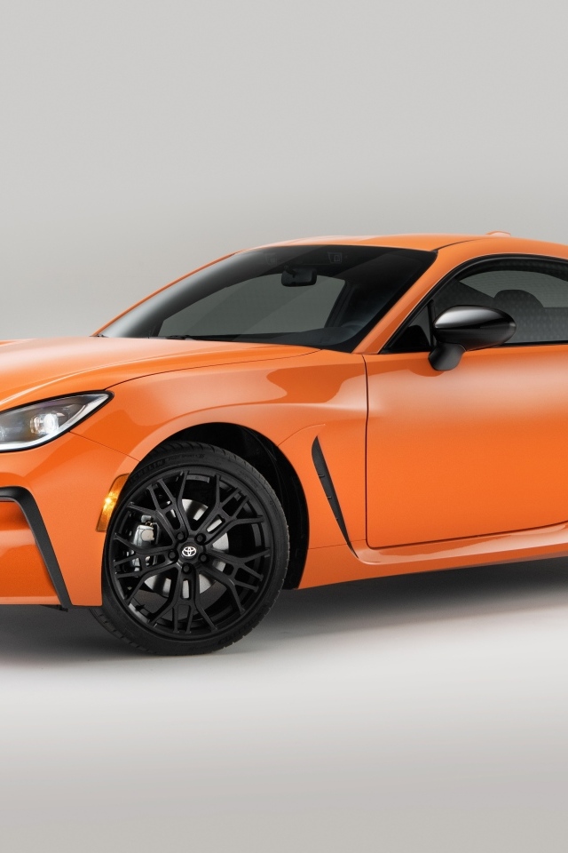 Оранжевый автомобиль Toyota GR 86 на сером фоне