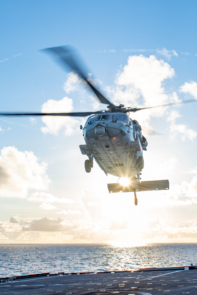 Военный вертолет приземляется на корабль в море