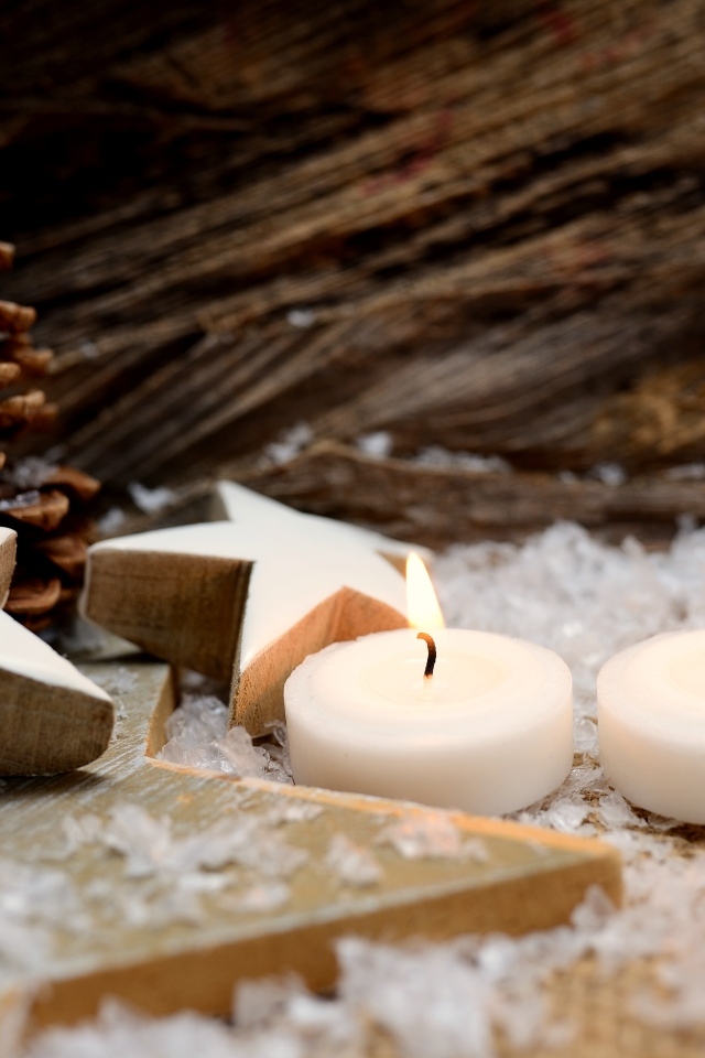 Две зажженные свечи, шишки и звезды