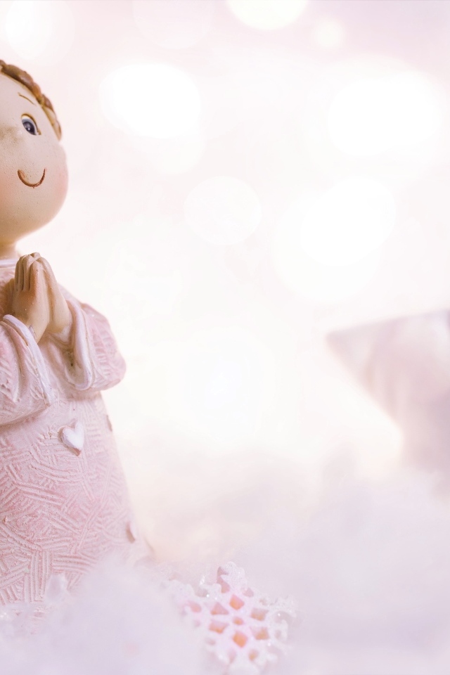 Маленькая статуэтка ангела стоит на снегу