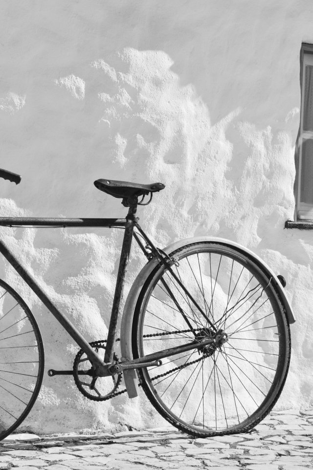 Черный велосипед стоит у белой стены