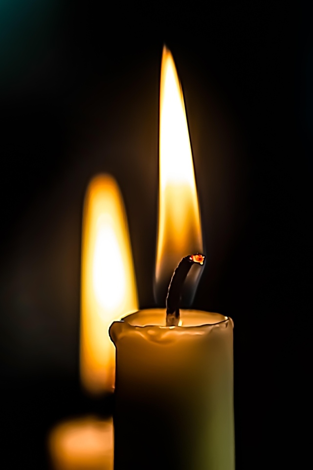 Зажженная свеча на черном фоне