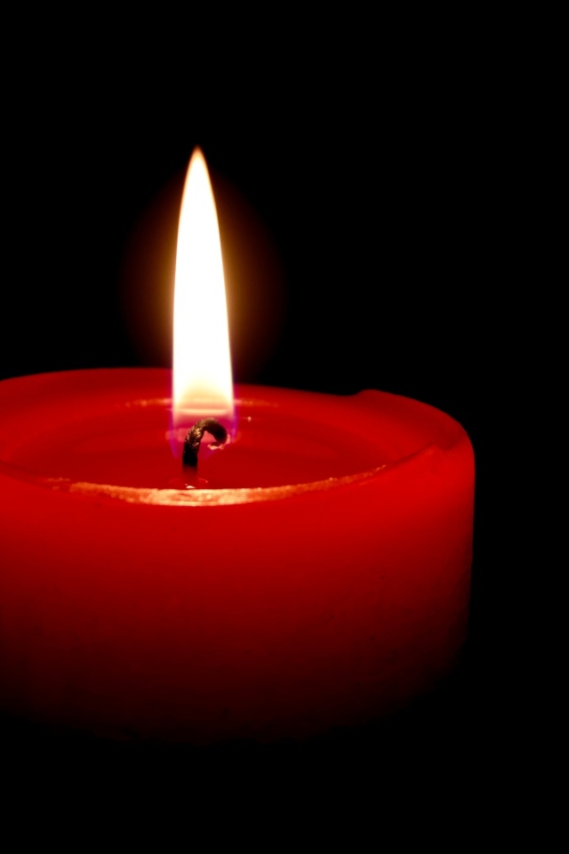 Зажженная красная свеча на черном фоне