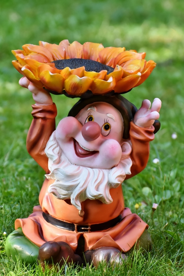 Садовая фигура гном за зеленой траве