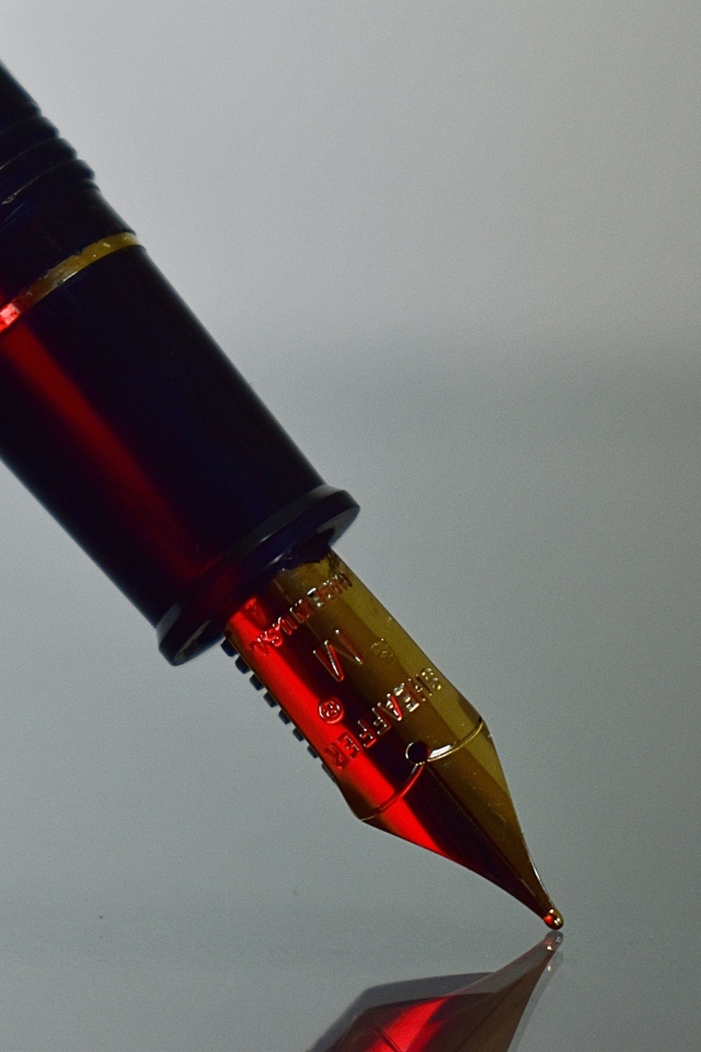 Золотое перо чернильной ручки на сером фоне