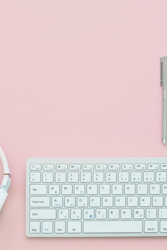 Наушники, клавиатура, блокнот с ручкой и мышка на розовом фоне