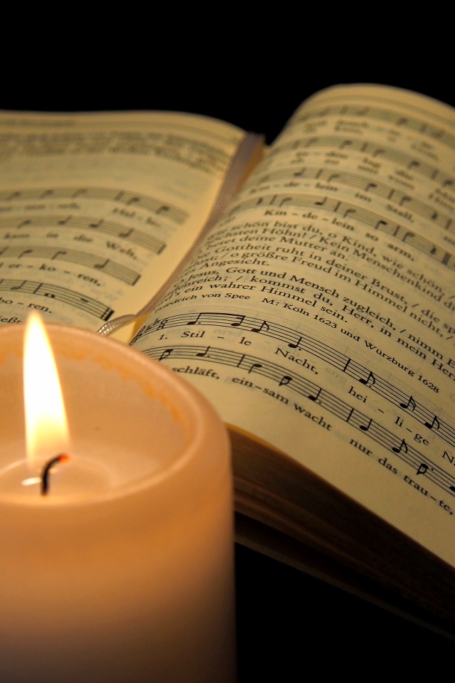 Зажженная свеча с книгой с нотами