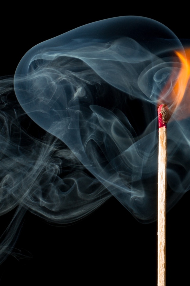 Зажженная спичка с дымом на черном фоне