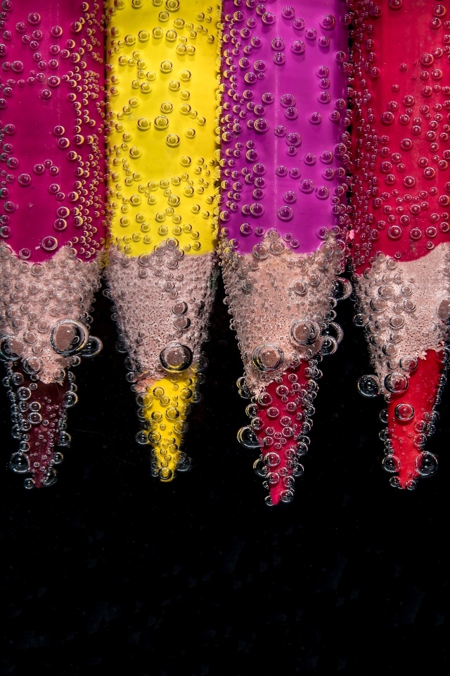 Разноцветные карандаши в пузырях воды на черном фоне