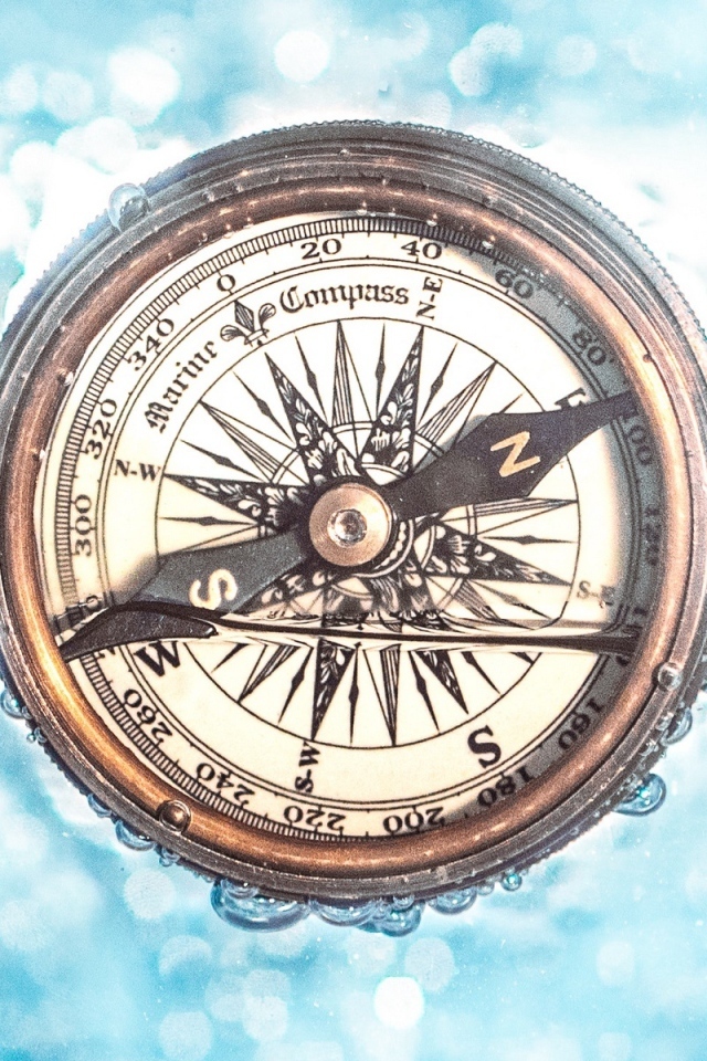 Старый компас в воде на голубом фоне