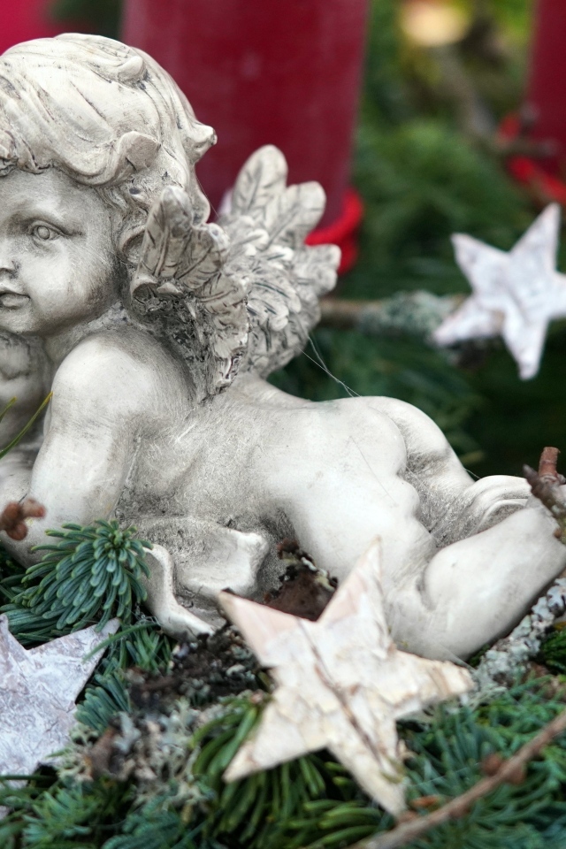 Статуэтка ангел лежит на ветках туи