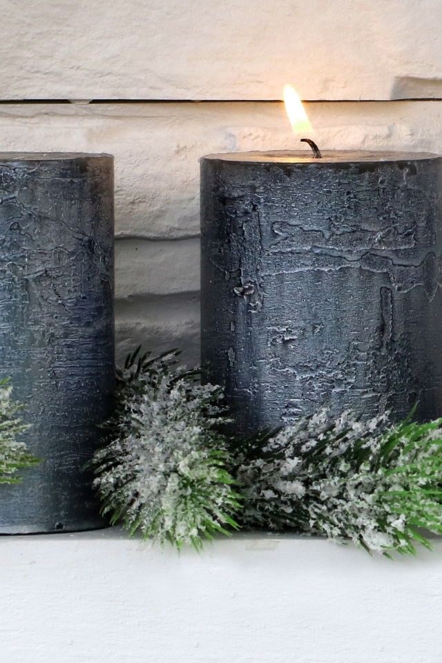 Две большие зажженные свечи у стены