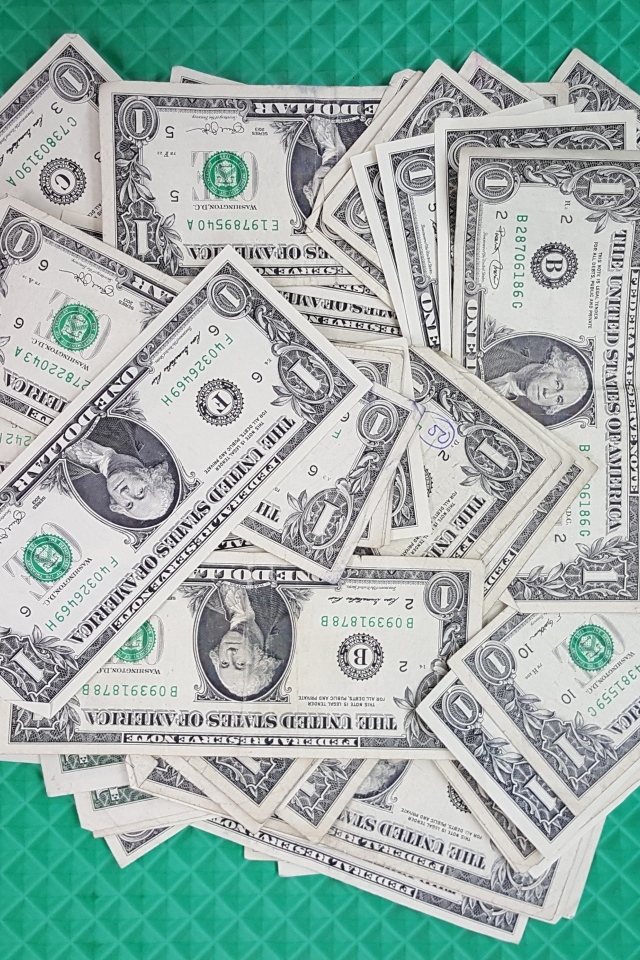 Много купюр в один доллар на зеленой поверхности