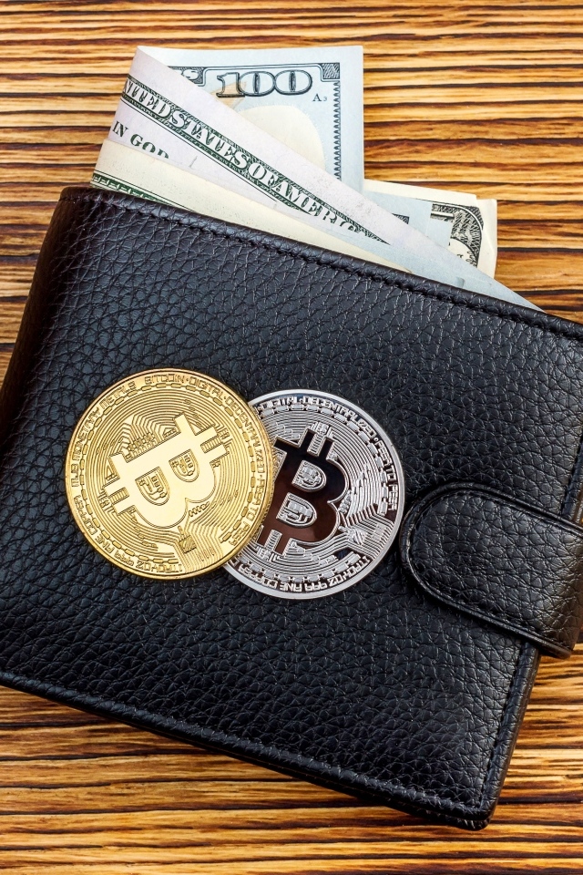 Черный кожаный кошелек с долларами и монетами биткоин