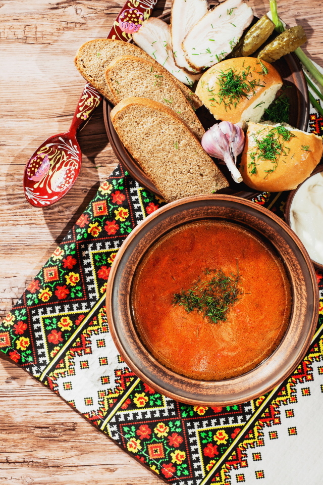 Тарелка борща на столе с салом, хлебом и зеленью