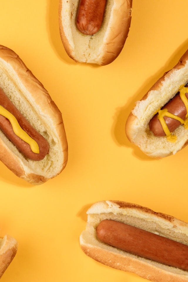 Аппетитные хот доги на желтом столе