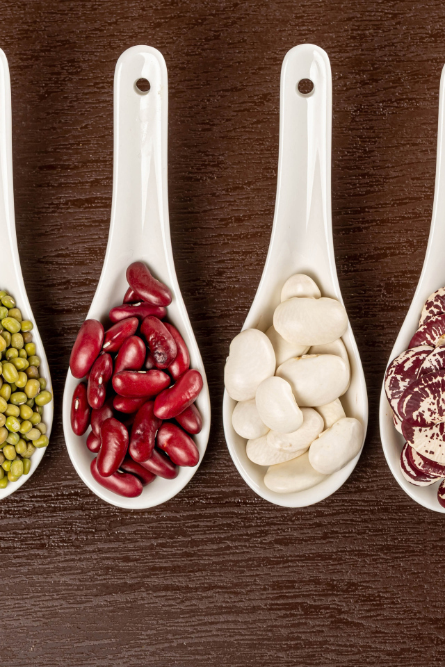 Бобовые зерна в белых ложках на столе
