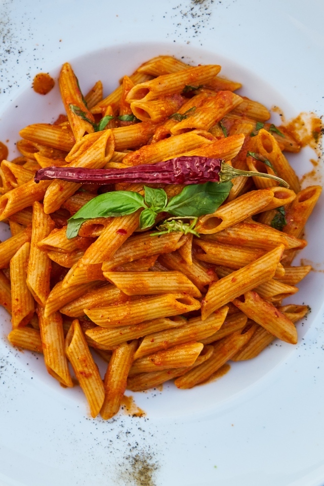 Вареные макароны на большой тарелке с красным перцем