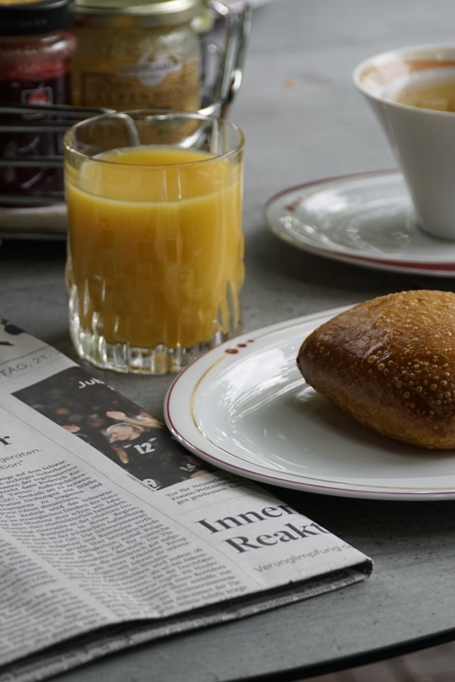 Булочка и стакан сока на столе с газетой