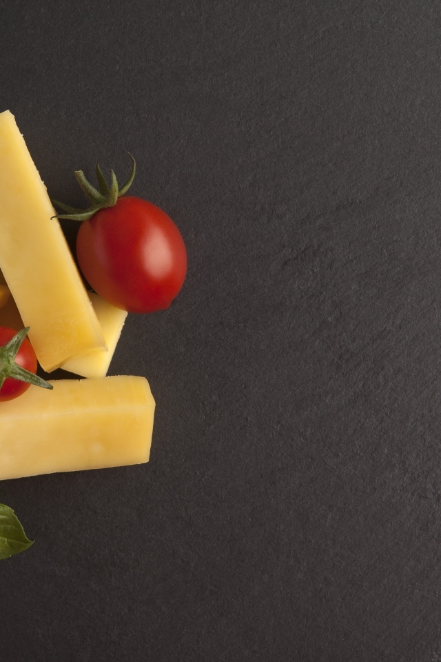 Сыр с помидорами и листьями базилика на сером столе