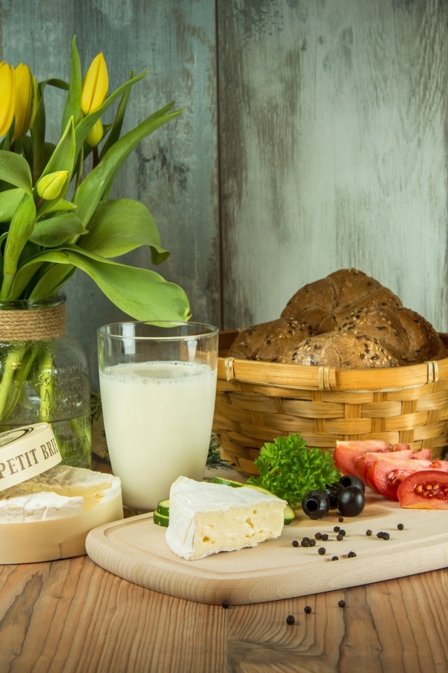 Сыр с овощами на столе с хлебом и букетом тюльпанов