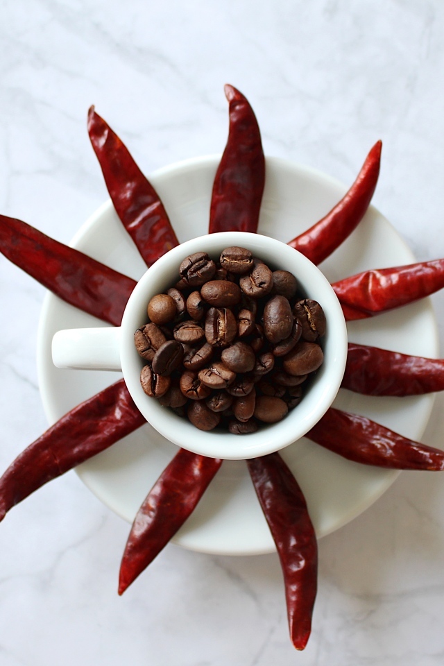 Кофейные зерна в чашке на тарелке с красным перцем