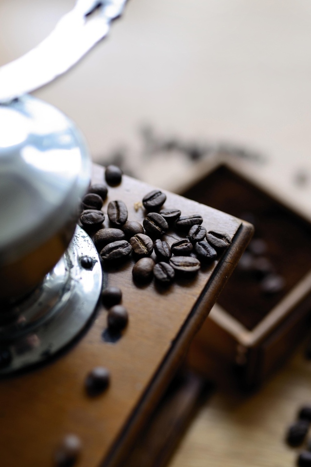 Кофемолка на столе с зернами