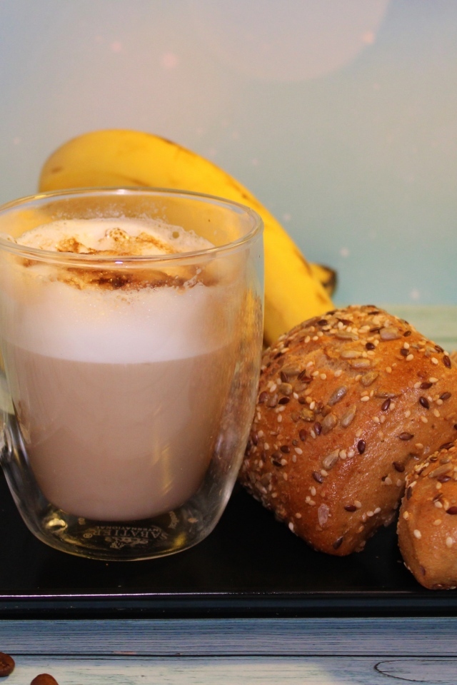 Чашка какао на столе с булочками и бананами