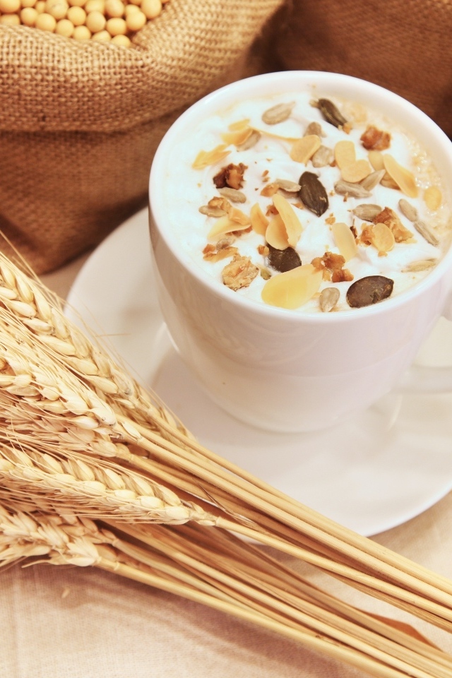 Чашка молока с хлопьями на столе с пшеницей