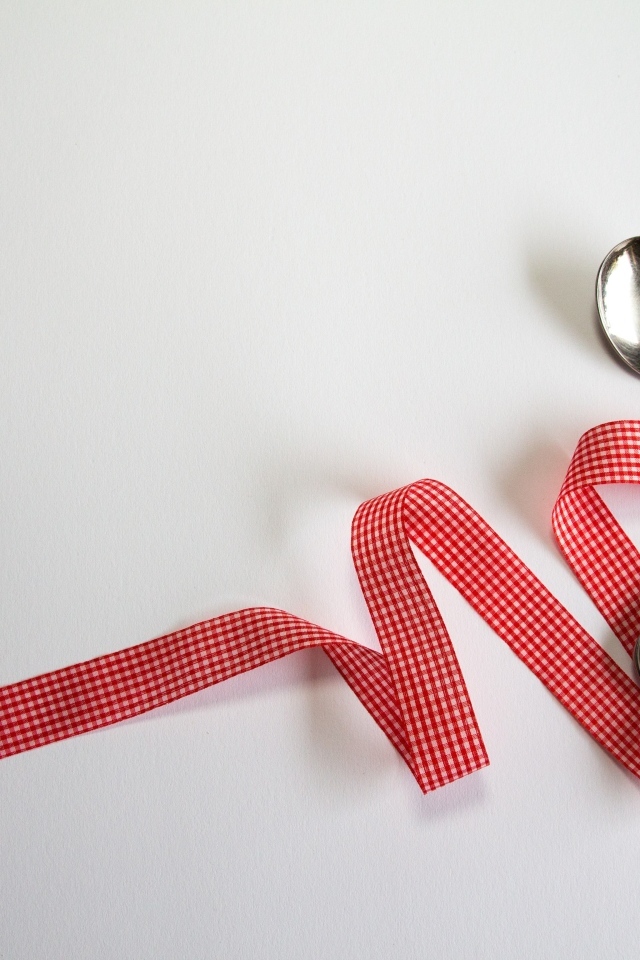 Столовые приборы перевязаны лентой на сером фоне