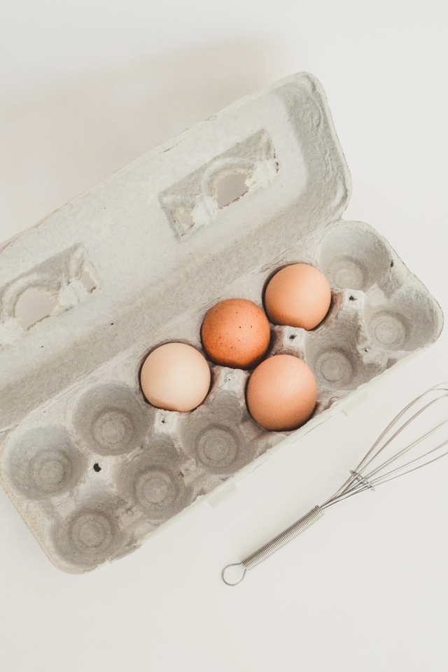 Четыре яйца в лотке на сером фоне