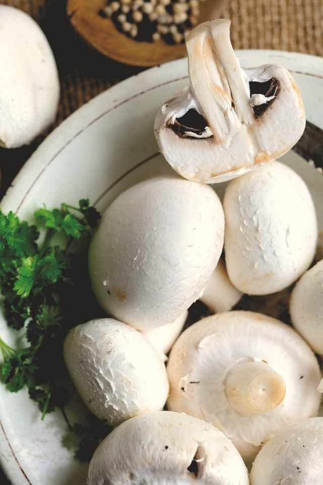 Свежие шампиньоны на тарелке на столе