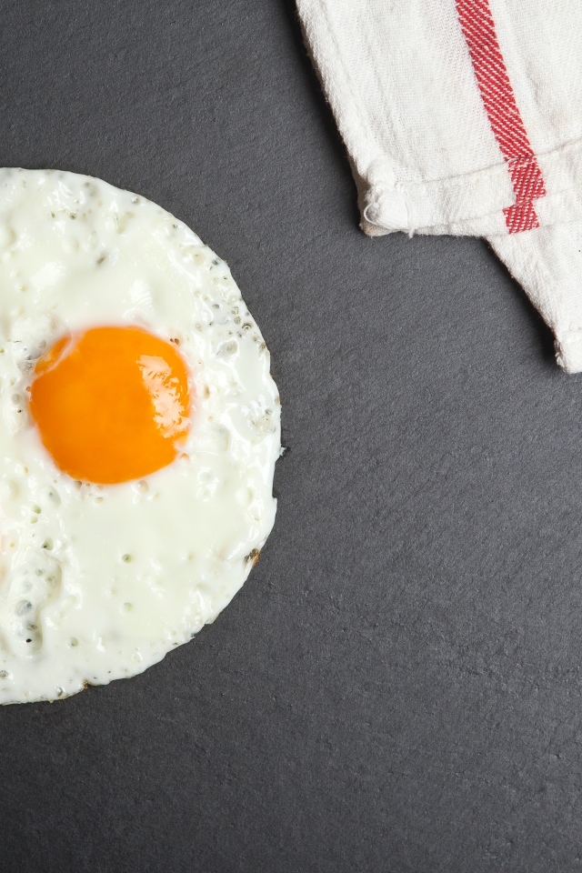 Яичница глазунья на сером столе с полотенцем