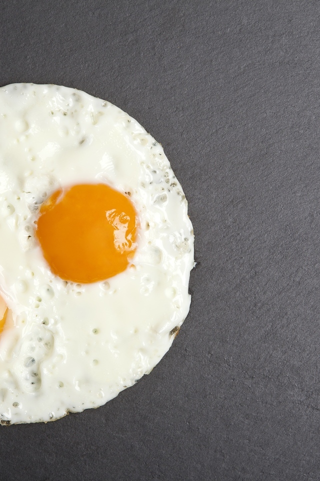 Яичница глазунья с вилкой на сером столе