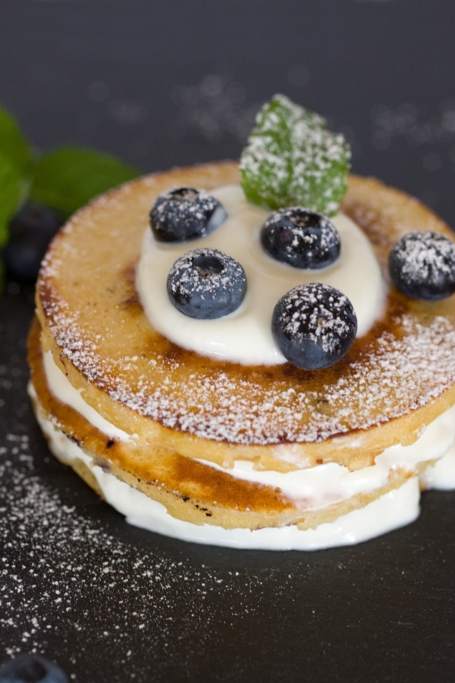 Оладьи с кремом и ягодами черники на столе