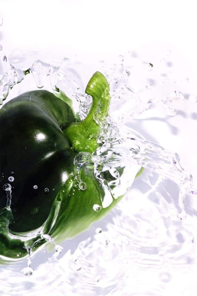 Зеленый перец в воде на белом фоне