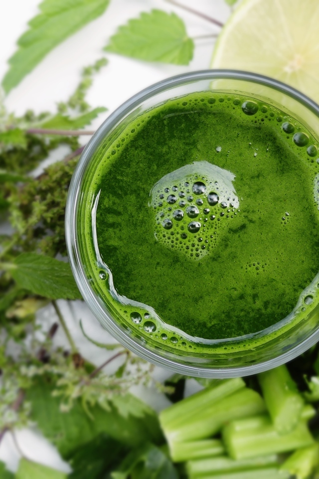 Зеленый овощной смузи в стакане на столе