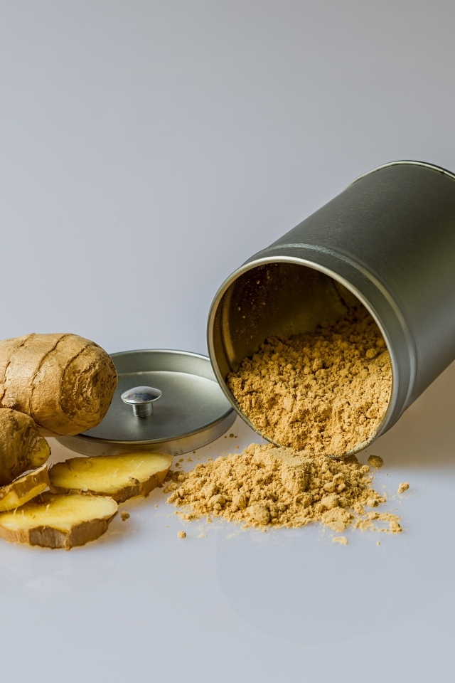 Молотый имбирь с корнем на сером фоне