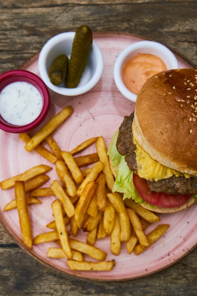 Гамбургер на тарелке с картофелем фри, огурцами и соусом