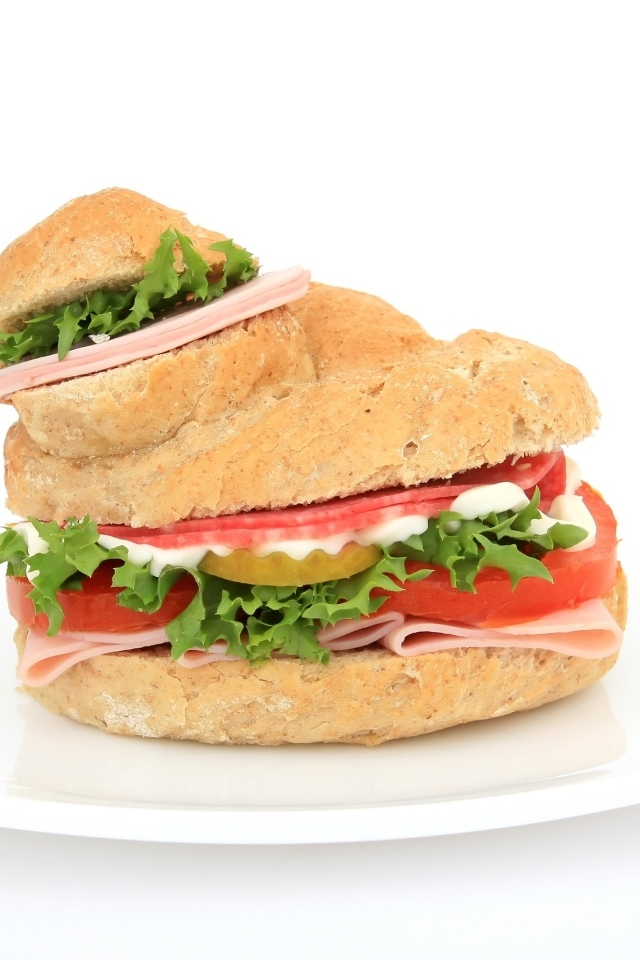 Гамбургер с колбасой, томатами и листьями салата на белом фоне