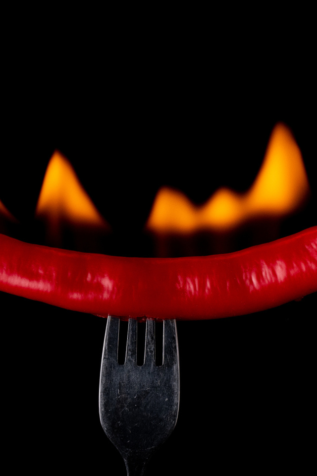 Жгучий красный перец на вилке на черном фоне