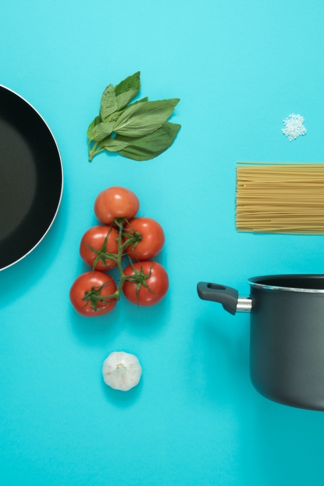 Ингредиенты и посуда для спагетти на голубом фоне